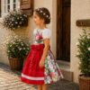 Mädchen in Seitenansicht im floralen Kinderdirndl Herzilein mit roter Schürze – Schnittmuster von TOSCAminni.