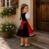 Seitenansicht des Kinderdirndls Herzilein mit schwarzem Rock und roter Schürze.