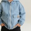 Genähte Kinderjacke Dotta nach Schnittmuster aus hellblauem Jeansstoff mit Kapuze und Gummizugbund.