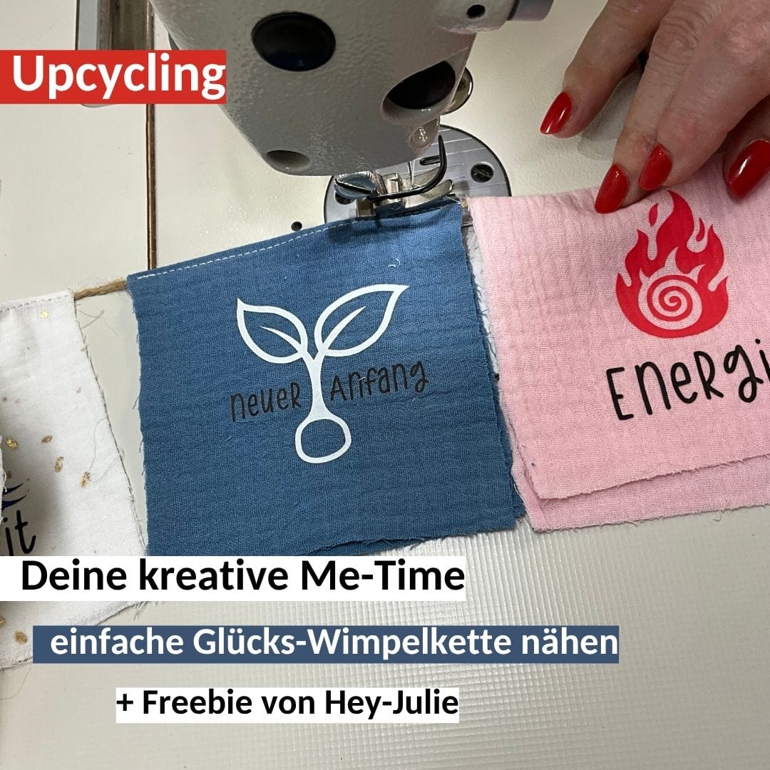 Einfache Wimpelkette nähen aus Musselin-Stoffresten mit einer Nähmaschine. Zu sehen sind zwei Stoffwimpel in Blau und Rosa, die mit weißen Plottermotiven wie einer Pflanze mit der Aufschrift neuer Anfang und einer Flamme beplottet sind.